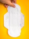 Woman is holding sanitary napkin in hand on yellow Royalty Free Stock Photo