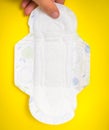 Woman is holding sanitary napkin in hand on yellow Royalty Free Stock Photo