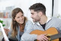 woman holding sheetmusic for man playing guitar Royalty Free Stock Photo