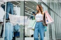 woman holding shopping bag and smartphone on her hands near the mall shop window Royalty Free Stock Photo