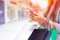 Woman holding shopping bags doing online shopping on her mobile Royalty Free Stock Photo