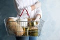 Woman holding shopping basket with products and toilet paper rolls on light blue background. Panic caused by virus Royalty Free Stock Photo