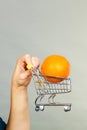 Woman holding shopping cart with orange inside Royalty Free Stock Photo