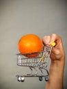 Woman holding shopping cart with orange inside Royalty Free Stock Photo