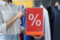Woman holding sign with designation of discount in store closeup