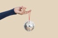 Woman holding silver christmas disco ball isolated on flesh color background Royalty Free Stock Photo