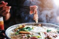 Woman holding sliced beef meat by chopsticks shabu shabu is Korean or Japanese style beef in hot pot dish of thinly sliced meat Royalty Free Stock Photo