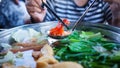 Woman holding sliced beef meat by chopsticks shabu shabu is Korean or Japanese style beef in hot pot dish of thinly sliced meat an Royalty Free Stock Photo