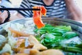 Woman holding sliced beef meat by chopsticks shabu shabu is Korean or Japanese style beef in hot pot dish of thinly sliced meat an Royalty Free Stock Photo