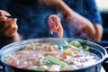 Woman holding sliced beef meat by chopsticks shabu shabu is Korean or Japanese style beef in hot pot dish of thinly sliced meat Royalty Free Stock Photo