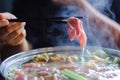 Woman holding sliced meat by chopsticks shabu shabu is Korean or Japanese style beef in hot pot dish of thinly sliced meat an Royalty Free Stock Photo