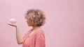 Woman holding small piggy bank in her hand and making funny faces. Big expectation small investment growth Royalty Free Stock Photo