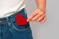 Woman holding a small sparkling red heart putting it in or taking off the pocket of her jeans. Sharing and receiving