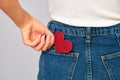 Woman holding a small sparkling red heart putting it in or taking off the pocket of her jeans. Sharing and receiving