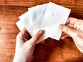 Woman Holding Small White Papers Over a Wooden Surface. Hands presenting several small white papers