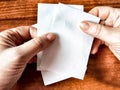 Woman Holding Small White Papers Over a Wooden Surface. Hands presenting several small white papers