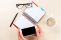 Woman holding smartphone above business desk