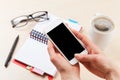 Woman holding smartphone above business desk