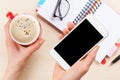 Woman holding smartphone above business desk