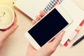 Woman holding smartphone above business desk