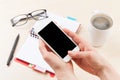 Woman holding smartphone above business desk