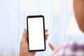 Woman holding smartphone with blank screen on blurred background, closeup of hands Royalty Free Stock Photo