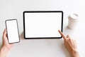 Woman holding smartphone and point digital tablet mockup of blank screen on the table. Royalty Free Stock Photo