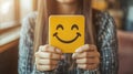Woman holding smiley face card, cafe setting, happy expression Royalty Free Stock Photo
