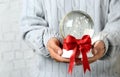 Woman holding snow globe with red bow on blurred background Royalty Free Stock Photo