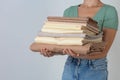 Woman holding stack of clean bed linens on light grey background. Space for text Royalty Free Stock Photo