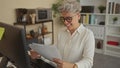 Woman holding stack of documents beside computer and making a fist pump in an office building; career success Royalty Free Stock Photo