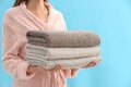 Woman holding stack of fresh clean towels on blue background, closeup Royalty Free Stock Photo