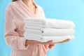 Woman holding stack of fresh clean towels on blue background, closeup Royalty Free Stock Photo