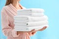 Woman holding stack of fresh clean towels on light blue background, closeup Royalty Free Stock Photo