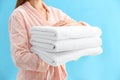 Woman holding stack of fresh clean towels on light blue background, closeup Royalty Free Stock Photo