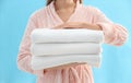 Woman holding stack of fresh clean towels on light blue background, closeup Royalty Free Stock Photo