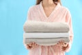 Woman holding stack of fresh clean towels on light blue background, closeup Royalty Free Stock Photo