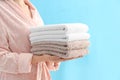 Woman holding stack of fresh clean towels on light blue background, closeup Royalty Free Stock Photo