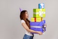 Woman holding stack of presents, having surprised excited facial expression, keeps mouth opened. Royalty Free Stock Photo