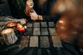 Woman holding staff, sitting at dark table with magic cards