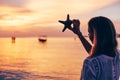 Woman holding starfish over sunset beach Royalty Free Stock Photo
