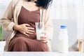 Woman holding stomachache and a glass of cow milk having gas, heartburn, feeling discomfort because of indigestion system