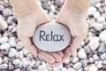 Woman holding stone with the word Relax in her palms