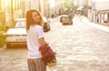 Woman holding straw bag with vivid bunch of lilac flowers walking down the street