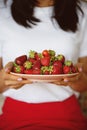 Woman holding strawberries in a plate.