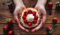 A woman holding a strawberry tart on a wooden table