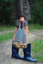 Woman holding string bag with potatoes.