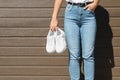 Woman holding stylish sneakers near wooden wall