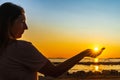 Woman holding sun in her palm, witch trough shines Sunstar with sunrays at sunset on beach Royalty Free Stock Photo