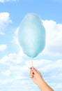 Woman holding sweet cotton candy on sky background, closeup view